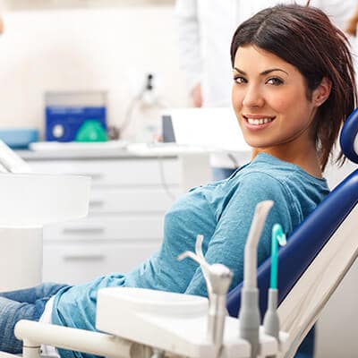 A young female patient in the dentist's chair smiling while waiting for her consultation