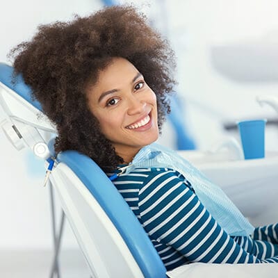 A female patient smiling and relaxed in the dental chair to show that Dr. Raval offers sedation dentistry at his dentist office