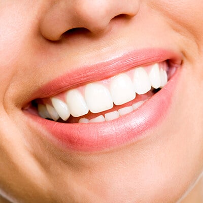 The smiling mouth of a young woman, showing her beautiful white teeth.